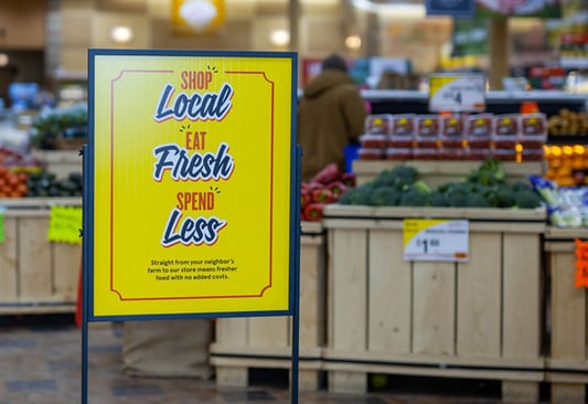 stanchion sign in store says "shop local; eat fresh; spend less"