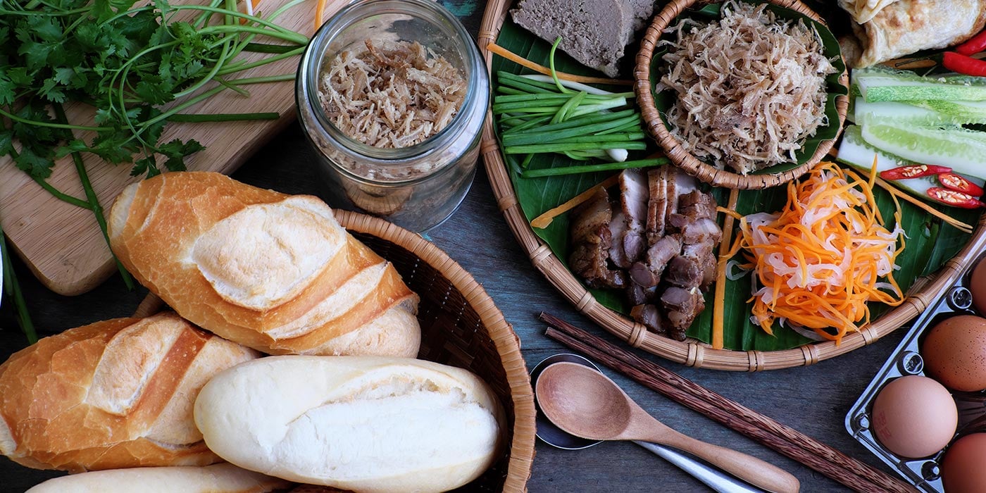 bread, cilantro, shredded carrots, pork, and other ingredients laid out for sandwiches