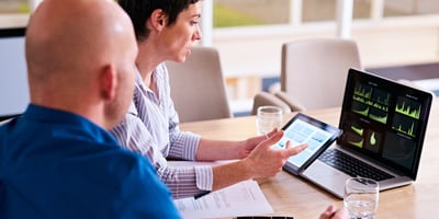 Two people talking in front of a laptop