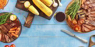grilled corn, zucchini, carrots, and steak on plates