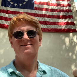 IGA CEO John Ross in front of a 13-star flag