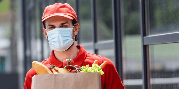 Grocery employee wears a mask with a bag of groceries