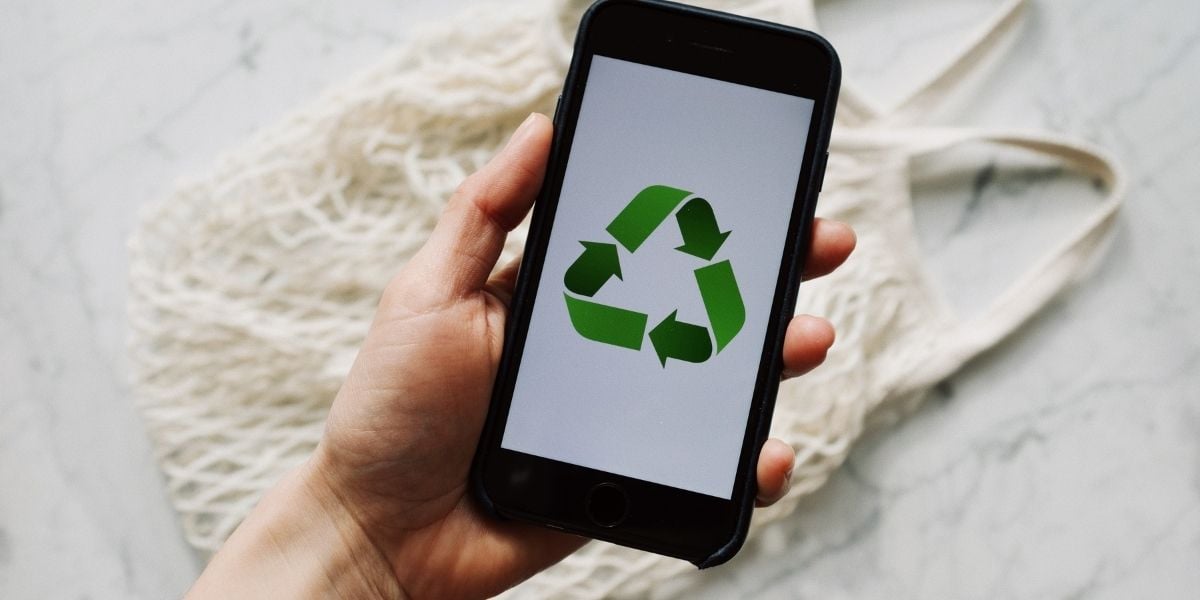 Recycle symbol on a mobile phone with tote in background