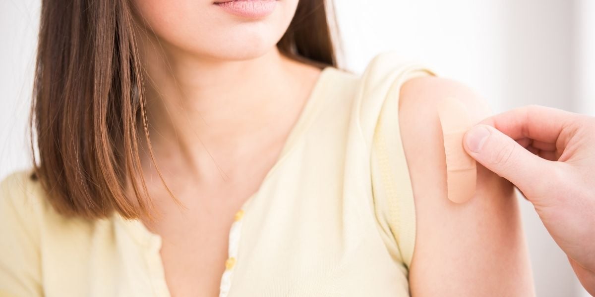 a woman receives a bandage on her arm post-vaccination