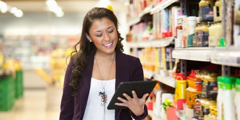 woman looking at tablet in grocery aisle