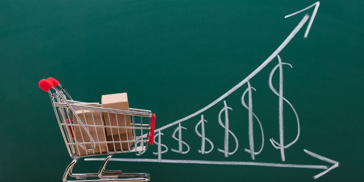 a grocery cart in front of a chalkboard with rising price symbols