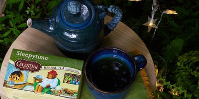 Celestial Seasonings Sleepytime tea sits on a table with teapot and mug next to a Christmas tree