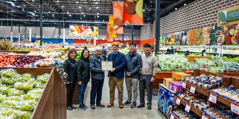 Yong Kim and John Ross hold the Retailer of the Year certificate among the Nam Dae Mun Farmers Market team in the store