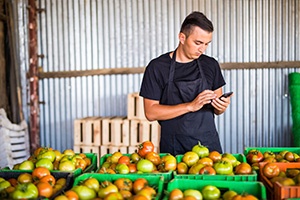guy in front of his produce looking at his phone
