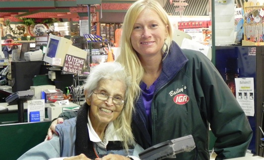 women in iga jacket posing with older woman in iga store