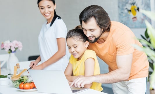 Family looking at laptop and cooking