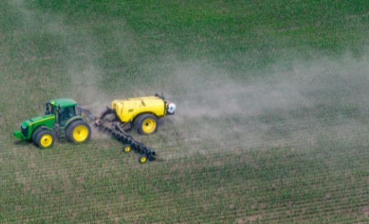 tractor distributes fertilizer in field