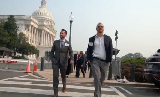 Two men walking with U.S. capitol hill in background